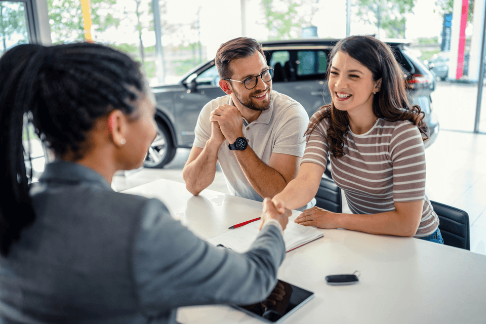 young couple closing on the purchase of a new car