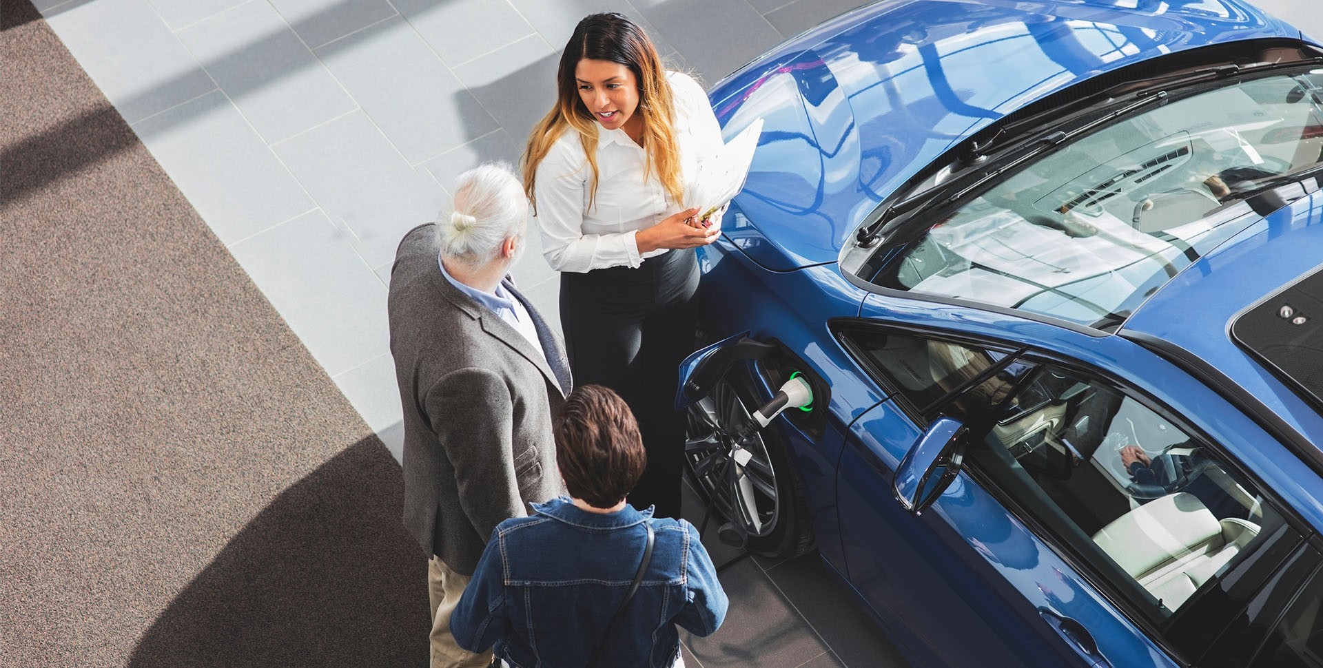 salesperson showing electric vehicle to customers in showroom